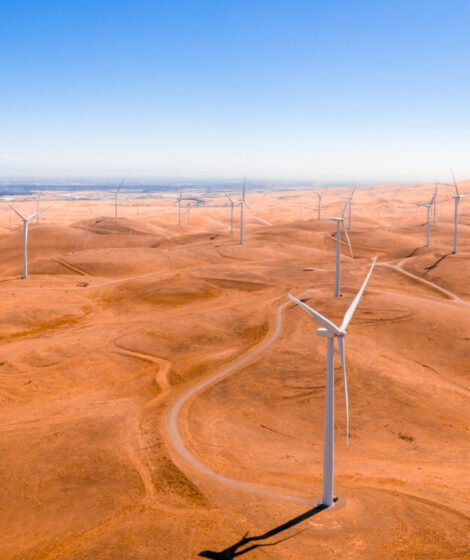 An aerial view of the wind turbines and curvy road on beautiful golden mountain landscape in California